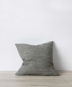 a black and white striped pillow sitting on top of a wooden floor next to a wall