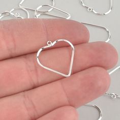 a hand holding a small silver heart charm