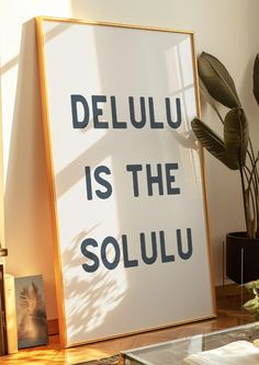 a poster with the words deluu is the solulu on it next to a potted plant