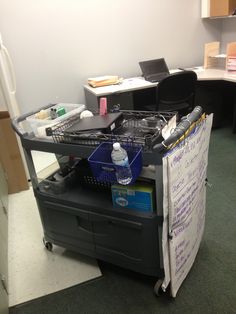 an office cubicle with a cart full of items