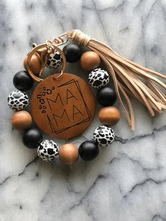 a personalized wooden charm with black and white beads, tassels and a leopard print tassel