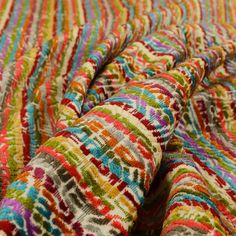 multicolored striped fabric is laying on top of the bed sheet and has an interesting pattern