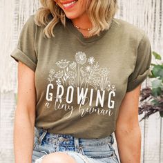 a woman wearing a brown t - shirt that says growing a tiny garden on it