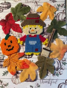 a cross stitch thanksgiving card with an image of a scarecrow, pumpkins and leaves