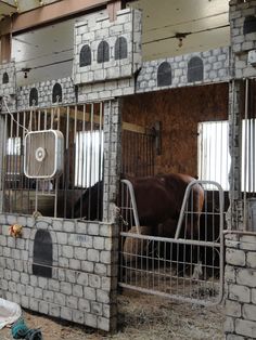 a horse is standing behind bars in an enclosed area that has been built into the side of a building