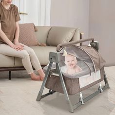 a woman sitting on a couch next to a baby in a bassinet with her feet up