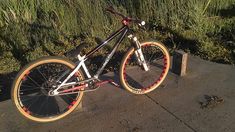 a bike that is sitting on the side of a road next to some grass and bushes