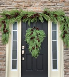 a christmas wreath on the front door of a house with pine cones and evergreen needles