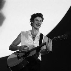 a man holding a guitar and smiling at the camera