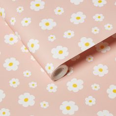 a pink wallpaper with white and yellow flowers on it, next to a roll of tape