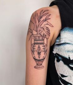 a woman with a tattoo on her arm has a potted plant in the vase