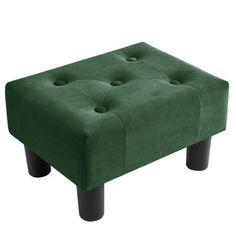 a green foot stool sitting on top of a white floor next to a black leg