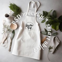 a white apron sitting on top of a table next to some plants and other items