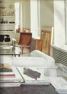 a living room filled with white furniture and lots of books on top of a table