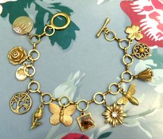 Beautiful vintage inspired bracelet with 12 plant and insect brass charms on a  brass round link chain. The charms are all 3d and include a real dried flower, a vintage enamel flower, rhinestones and coloured glass cabochon to add interest and extra detail.  The bracelet is a lovely golden colour which has been polished and coated in a protective wax but as with all brass jewellery it will darken with time but can be repolished or left to form a natural patina as desired. The bracelet will be supplied in a velvet gift pouch. Vintage Charm Brass Bracelet, Gold Bohemian Charm Bracelet Nickel Free, Bohemian Gold Metal Charm Bracelet, Gold Bohemian Bracelets With Charms, Bohemian Gold Bracelets With Charms, Gold Brass Charm Bracelet With Vintage Charm, Bohemian Gold Charm Bracelet With Lobster Clasp, Gold Bohemian Charm Bracelet With Lobster Clasp, Bohemian Gold Brass Charm Bracelet