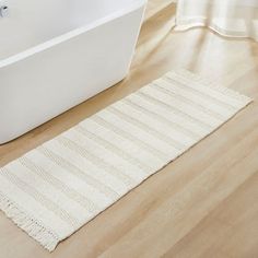 a bath tub sitting next to a white rug on top of a hard wood floor