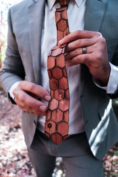 a man wearing a suit and tie is holding his hand on the wooden necktie