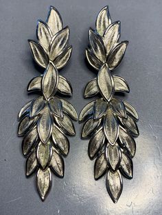 LOVELY TRIFARI VINTAGE 1980's Silver leaf Design Long Dangly Drop Clip On Earrings Signed Statement Elegant Glamour Runway Designer Couture. Wonderful earrings with a push back clip in a fantastic leaf design, signed on the clip at the back with the crown above Trifari. Measurements: 6.6cm by 2.2cm Condition: In ABOVE excellent vintage condition, The clips are secure and tight. Please look at the photos as they are truly representative of the condition of this amazing earrings. All our items are priced including delivery tracked and signed for and tracking number will be provided after postage.   Don't hesitate to ask any questions or need further information. Use the discount code WAYOFLIFE20 to receive €20 discount when purchasing two items from our shop. PLEASE FEEL FREE TO CHECK OUT OU Silver Leaf-shaped Earrings For Party, Silver Leaf-shaped Jewelry For Party, Leaf-shaped Metal Earrings For Party, Leaf-shaped Metal Jewelry For Party, Leaf-shaped Metal Party Jewelry, Amazing Earrings, Silver Leaf, Leaf Design, Clip On