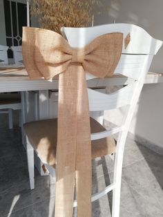 a chair with a bow on it sitting in front of a white dining room table