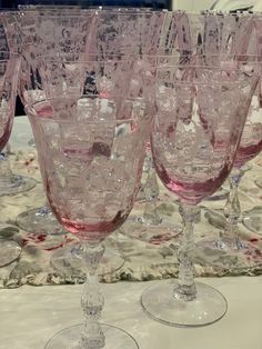 many wine glasses are lined up on a tableclothed cloth, with one empty glass in the middle