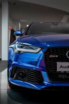 the front end of a blue car in a showroom