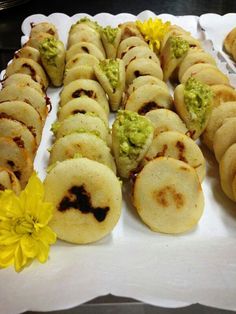 some food is laying out on a white tray with yellow flowers in front of it