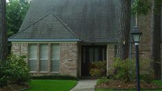 a brick house with trees and bushes around it