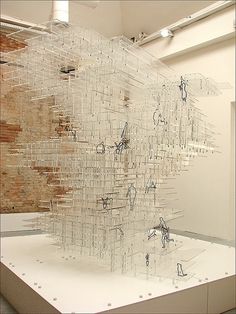 an art piece is displayed on a white surface in front of a brick wall and ceiling