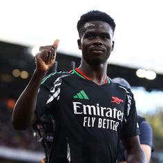 a soccer player is giving the peace sign with his hand while standing in front of an audience