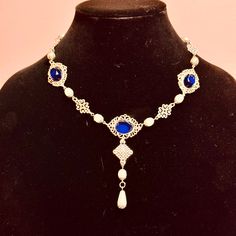 Handcrafted replica period jewelry, made to imitate the style and grandeur of the Tudors. This elegant necklace will complement any renaissance garb, and elevate even the most simple gown into a piece fit for a queen. It is made to order in your choice of gold, silver, or bronze and can be set with resin gemstones of just about any color. Ruby, emerald, sapphire, amethyst and onyx are most popular options. It is accented with beautiful mix of pearls sandwiched between matching metal bead caps, and metal filigree pieces. A teardrop pearl dangles beautifully in front. Elegant Baroque Necklace With Historical Design, Baroque Necklace With Historical Design As A Gift, Baroque Historical Design Necklace For Gift, Baroque Necklace With Historical Design For Weddings, Baroque Necklaces With Historical Design For Wedding, Baroque Historical Design Necklace For Wedding, Baroque Wedding Necklace With Historical Design, Elegant Historical Pendant Necklaces, Elegant Costume Jewelry Choker