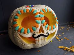 a decorated pumpkin with a mustache and flowers on it