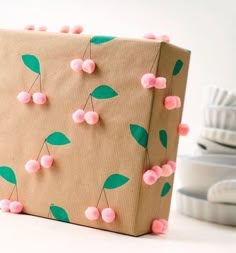 a brown paper bag with pink pom - poms and green leaves on it