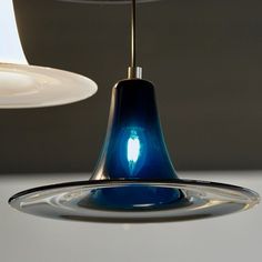 a blue light hanging from a ceiling in a room with a lamp on the other side