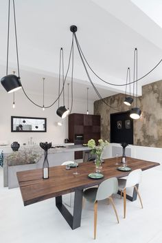 a dining room table with chairs and lights hanging from the ceiling