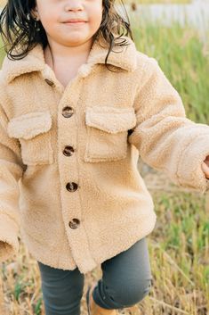 Keep your little one cozy + stylish with the Sherpa Shacket. This adorable shacket is designed for babies + toddlers up to 5T, providing warmth + comfort during chilly days. Made from soft + plush sherpa material, it is gentle on delicate skin. The shacket features a trendy design that can be easily layered over any outfit, making it a versatile addition to your child's wardrobe. 100% Cotton Wash in cold water, Tumble dry low. Runs oversized, size down one size! Length: 0-3m 11, 3-6m 11.75, 6-12 Cute Cream Outerwear, Cute Cream Long Sleeve Outerwear, Fleece-lined Outerwear For Playtime In Fall, Fleece-lined Outerwear For Fall Playtime, Fall Outerwear With Fleece Lining For Playtime, Cute Cream Winter Outerwear, Casual Warm Outerwear For Playtime, Casual Winter Outerwear For Playtime, Cute Fall Outerwear With Buttons