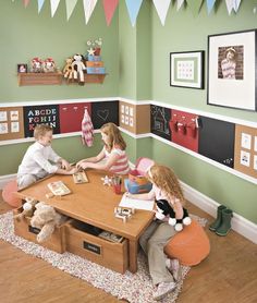 three children sitting at a table in a playroom