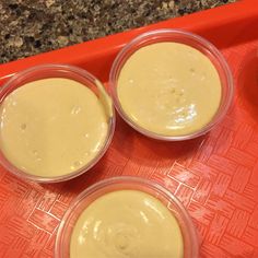 three small bowls filled with batter sitting on top of a red tray