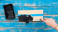 a person using a paint roller to paint a piece of wood