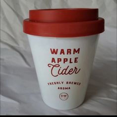 a cup of coffee sitting on top of a white tablecloth covered bed sheet with the words warm apple cider printed on it