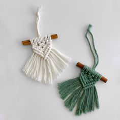 two tasselled pieces of white and green yarn with wooden handles, on top of each other