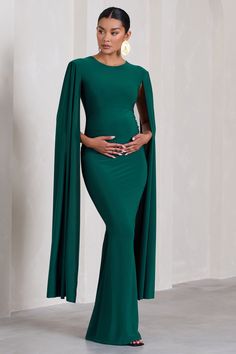 Sculpt your silhouette in our latest maternity design. Divine Timing. Arriving in a rich green shade. this maxi dress has everything you need to stand out from the crowd at your next black tie event. What defines this opulent piece is its long cape sleeves and floor-sweeping length. For the perfect wedding guest ensemble. try styling Divine Timing with a sleek bun and some statement earrings. Features - Premium stretch jersey- Button-closed crew neckline- Keyhole cut-out- Long cape sleeves- Invi Maternity Evening Gowns, Dress With Cape Sleeves, Maternity Evening, Dress With Cape, Long Cape, Club L London, Sleek Bun, Maternity Maxi Dress, Divine Timing