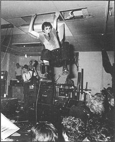 a man standing on top of a stage with his arms in the air while people watch