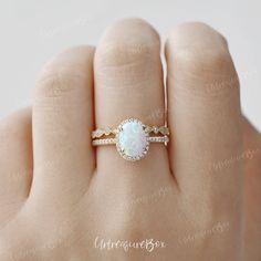 a woman's hand with a ring that has a white opal in it