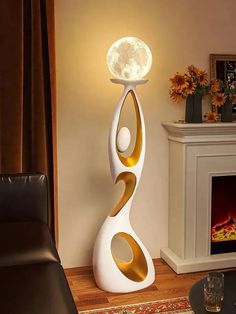 a white and gold lamp sitting on top of a table next to a fire place