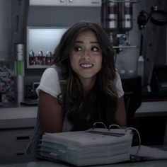 a woman sitting at a table with stacks of folders in front of her smiling