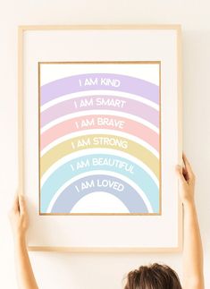 a person holding up a framed poster with the words i am kind in different colors