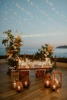 an outdoor dining area with candles and flowers on the table, lights strung over the tables