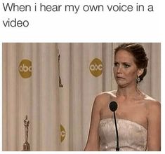 a woman standing in front of a microphone with the caption when i hear my own voice in a video