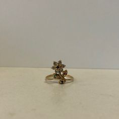 a gold ring with flowers on it sitting on top of a white countertop next to a wall