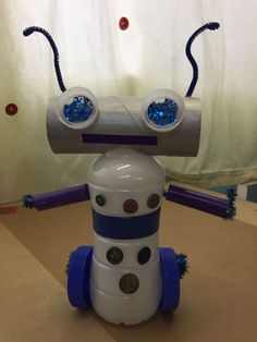 a white and blue robot toy sitting on top of a wooden table next to a curtain